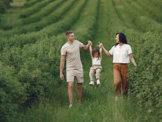 A happy family walking in a lush, green rural field together.
